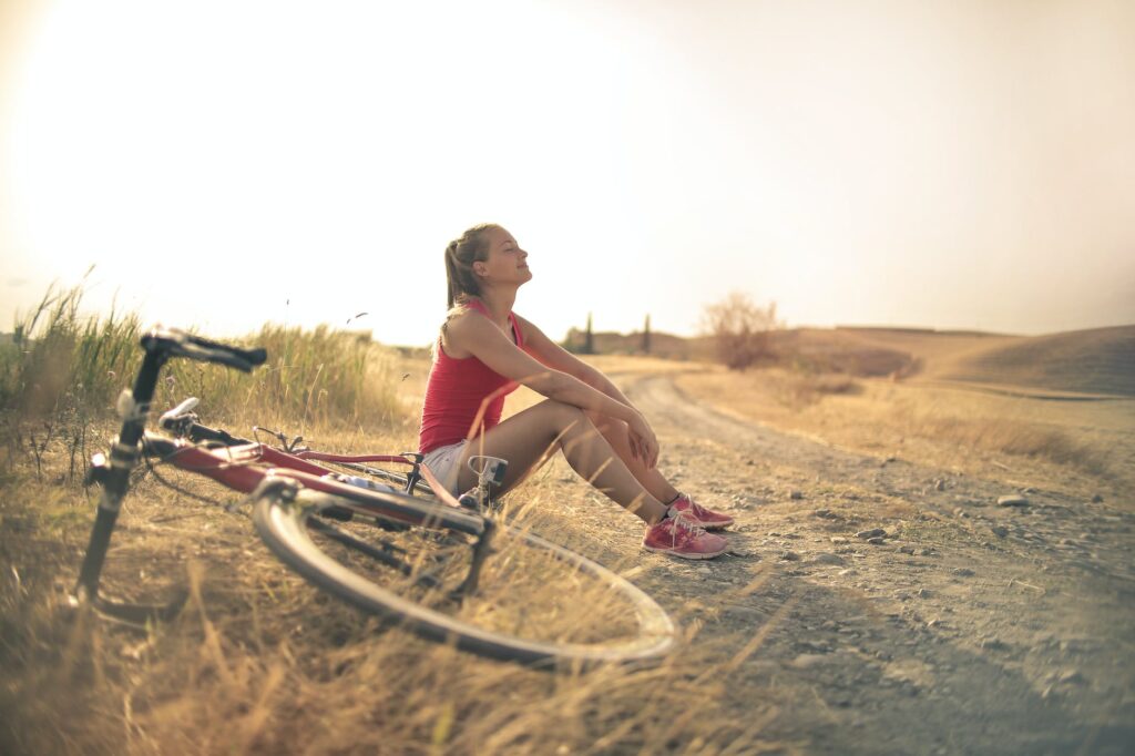 Services Naturopathic Functional Medicine sportive woman with bicycle resting on countryside road in sunlight